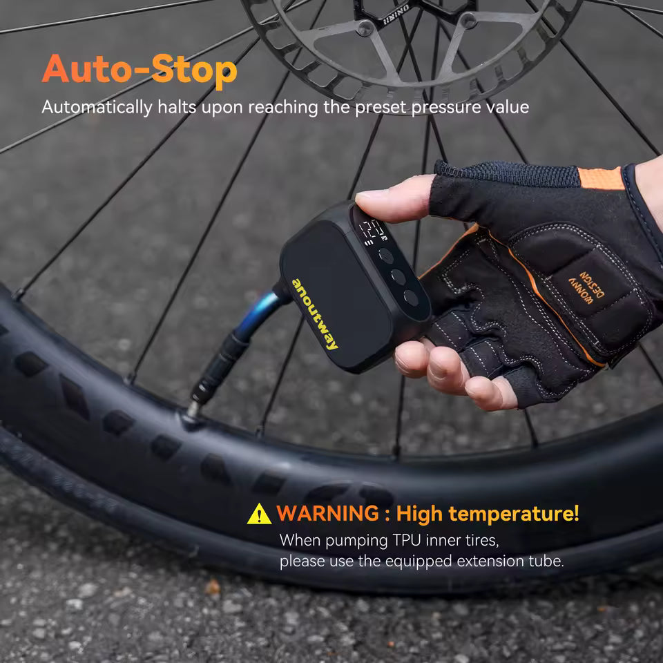 Hand using a bicycle air pump with 'Auto-Stop' feature and warning label on a tire.