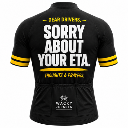 Black short-sleeve cycling jersey shown from the back with bold white and yellow text reading “DEAR DRIVERS, SORRY ABOUT YOUR ETA. THOUGHTS & PRAYERS.