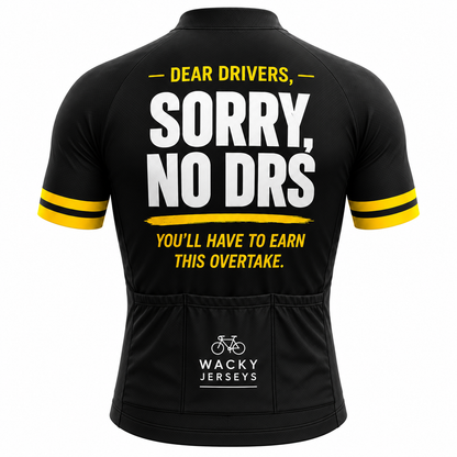 Black short-sleeve cycling jersey shown from the back with bold white and yellow text reading “DEAR DRIVERS, SORRY, NO DRS” and “YOU’LL HAVE TO EARN THIS OVERTAKE.” The back pockets show the Wacky Jerseys logo.