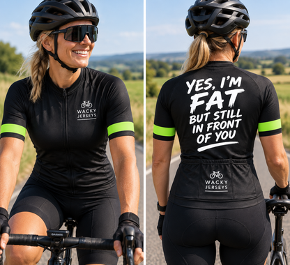 A woman wearing a black cycling jersey and shorts is shown from the front and back on a road bike outdoors. The front has a small white 'WACKY JERSEYS' logo on the chest, and the back has large white text reading 'YES, I'M FAT BUT STILL IN FRONT OF YOU' above the same brand logo.